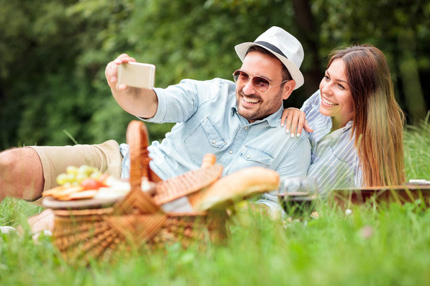 Boldog fiatal pár vesz egy selfie, miközben időt piknik a parkban - Fotó, kép