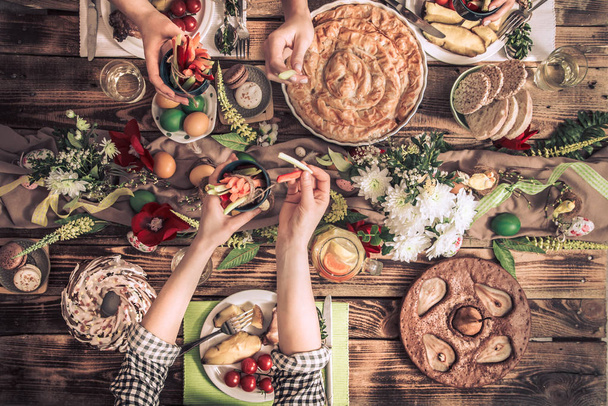 Appartamento-festa di amici o familiari al tavolo festivo con carne di coniglio, verdure, torte, uova, vista dall'alto
. - Foto, immagini