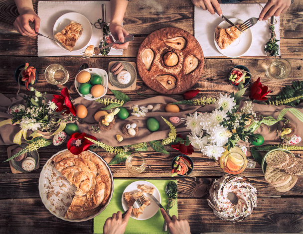 Apartman-családi ünnep, barátok vagy család az ünnepi asztalnál nyúlhússal, zöldségekkel, pitékkel, tojással, felülnézetben. - Fotó, kép