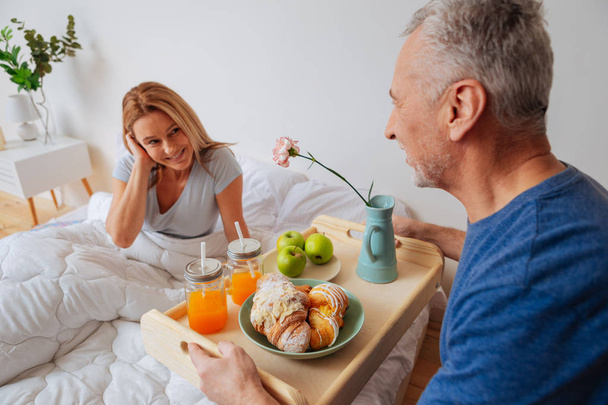 Wife looking at husband holding tray with breakfast and flowers - Fotografie, Obrázek