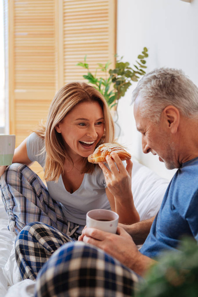 Husband and wife enjoying yummy croissants and coffee in bed - Foto, Bild