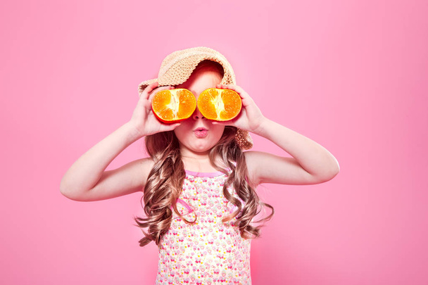lustige kleine Mädchen mit Zitrusfrüchten auf farbigem Hintergrund - Foto, Bild