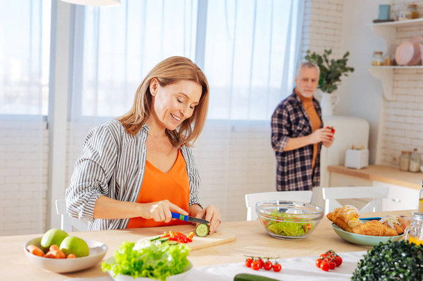 Beaming wife cutting vegetables for garden salad in the morning - Φωτογραφία, εικόνα