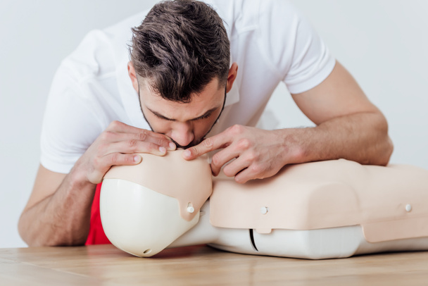 man using mouth to mouth technique on dummy during cpr training isolated on grey - Photo, Image