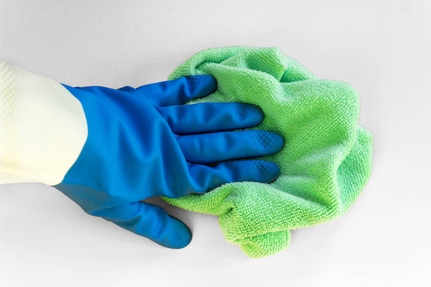 Käsi sinisessä kumihanskassa pitää kirkasta mikrokuitupölyä valkoisella pohjalla. Käsite kirkas kevät, kevätsiivous
 - Valokuva, kuva