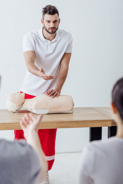 handsome instructor with cpr dummy gesturing during first aid training class - Photo, Image