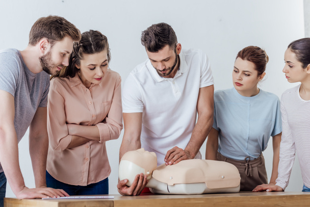 group of concentrated people with cpr dummy during first aid training class - Φωτογραφία, εικόνα