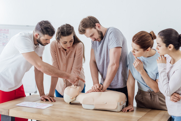 group of people with instructor performing cpr on dummy during first aid training - Photo, Image