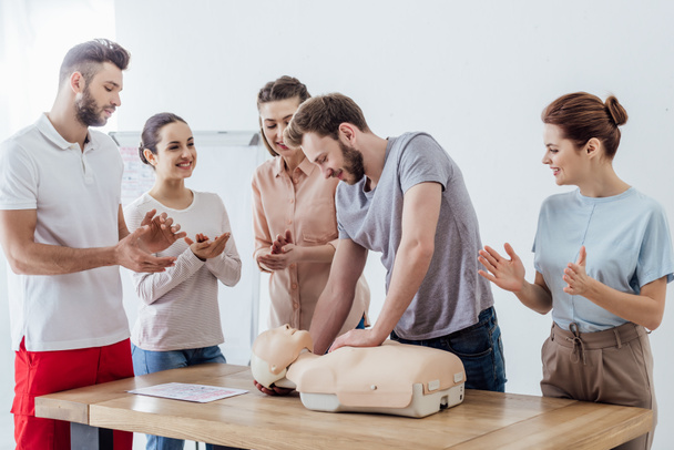 group of people applauding while man performing cpr on dummy during first aid training - Photo, Image