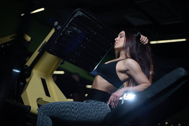 Fitness girl posing in the gym, showing off her body and relaxing after a workout - Fotografie, Obrázek
