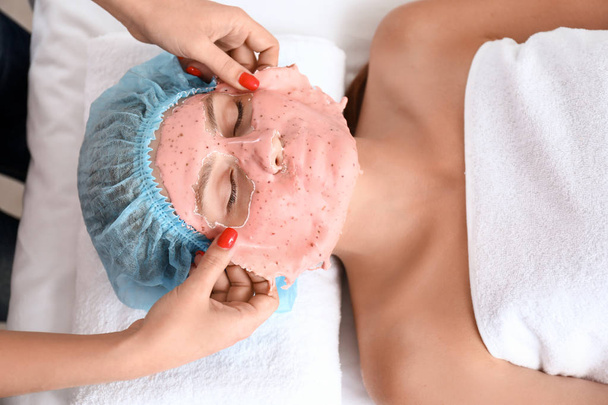 Cosmetologo rimuovere maschera di alginato dal viso della giovane donna nel salone di bellezza
 - Foto, immagini