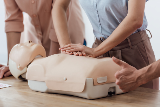 cropped view of woman performing chest compression on dummy during cpr training class while man doing thumb up sign - Φωτογραφία, εικόνα