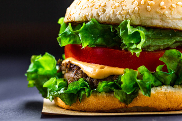 Deliciosa hamburguesa casera fresca sobre un fondo oscuro. Comida rápida y mala
  - Foto, imagen