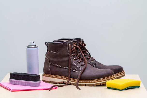 close-up shot of brown leather boots with cleaning supplies - Fotó, kép