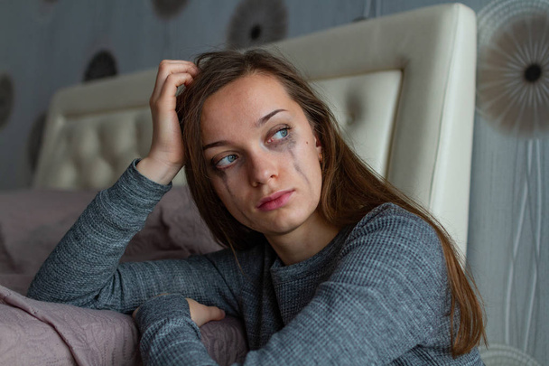 Depressed, sad, lonely woman sitting near the bed and crying because of problems at work and troubles in relationships. Domestic, woman violence. Life problems  - Photo, image