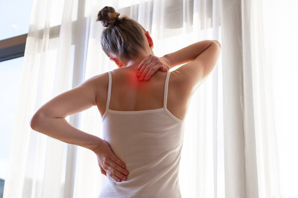 Young woman suffering from neck pain and backache, stretching the muscles at home. back and neck pain woman - Fotó, kép