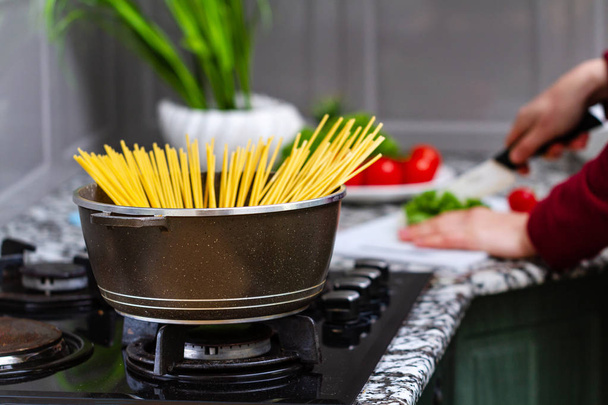 Cooking spaghetti in a saucepan in a kitchen at home.  - Φωτογραφία, εικόνα