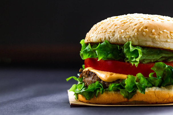 Delicious fresh homemade burger on a dark background. Fast and bad food  - Fotografie, Obrázek