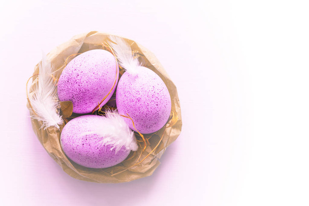 Easter pink eggs in a decorative nest on light background, top view, copy space - Foto, afbeelding