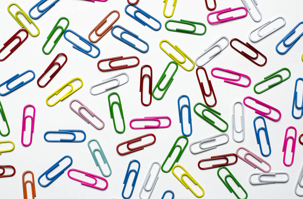 trombones colorés à des documents couchés sur un fond blanc
 - Photo, image
