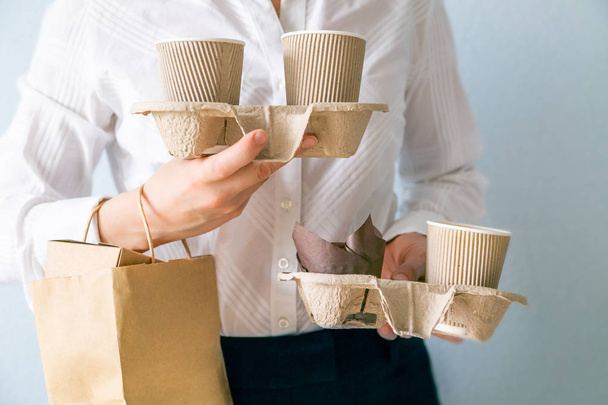 Female holding coffee containers, paper bag withfood containers. Food and coffee delivery - Foto, Imagen
