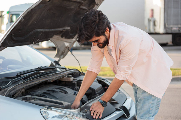 Jeune homme essayant de réparer une voiture cassée
 - Photo, image