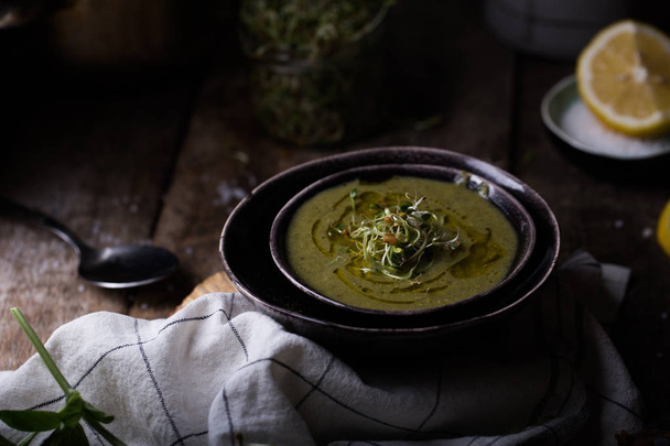 soup with green peas and spinach in black bowl in wooden background, selective focus - Photo, image