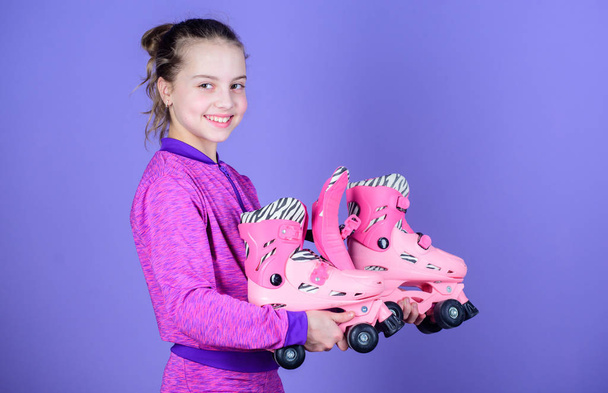 Hobby and active leisure. Happy childhood. Pick proper roller skates size. Why kids love roller skates. Roller skates every girl dreaming about. Lets ride. Girl cute little child hold roller skates - Φωτογραφία, εικόνα