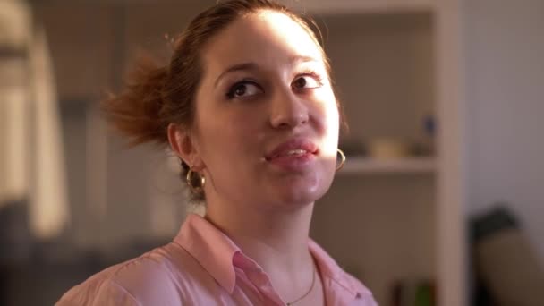 close view young beautiful woman with golden earrings in pink blouse smiles in room lit by sunlight - Filmmaterial, Video