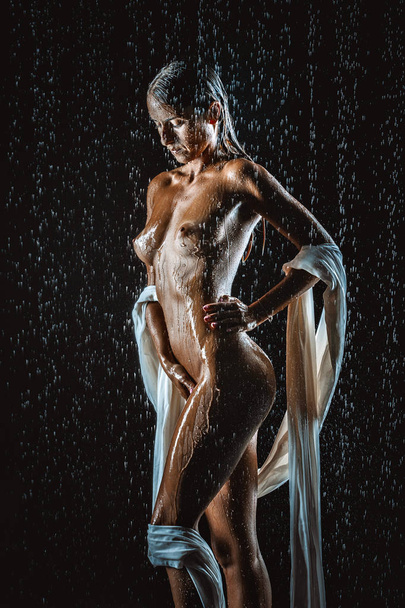 beautiful nude young woman under rain on black - Foto, afbeelding