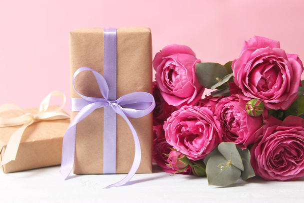 regalo y flores en un fondo coloreado. Vacaciones, danos un regalo, enhorabuena. Día de San Valentín, Día de la Madre, Día Internacional de la Mujer. - Foto, imagen