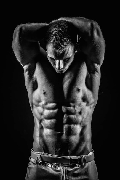 black and white shot of handsome muscular man isolated on black - Fotó, kép
