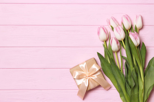Un ramo de hermosos tulipanes y un regalo en una vista de fondo de madera. Día de la Mujer, Día Internacional de la Mujer. Vacaciones, regalo. - Foto, Imagen