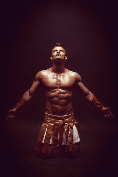 handsome muscular man in roman warrior costume on black - 写真・画像