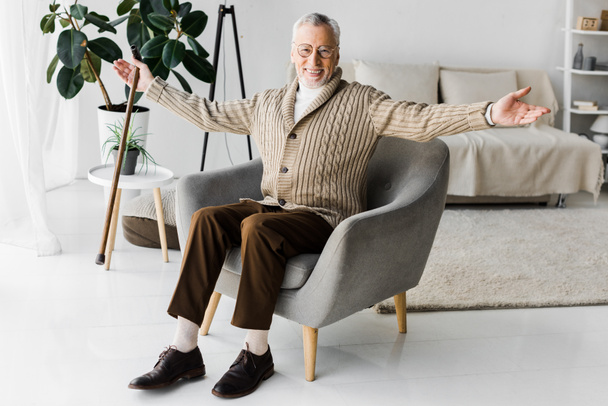 hombre jubilado feliz en gafas sentado en sillón con las manos extendidas
 - Foto, Imagen