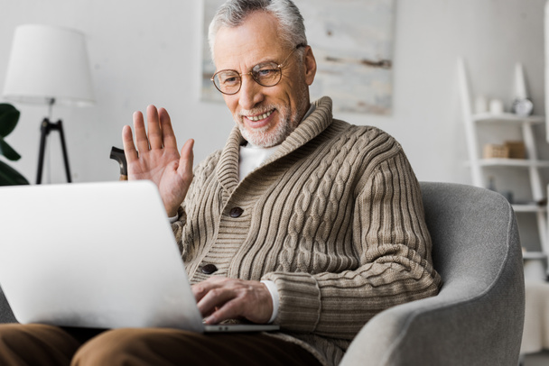 cheerful senior man in glasses waving hand while having video call - Photo, Image