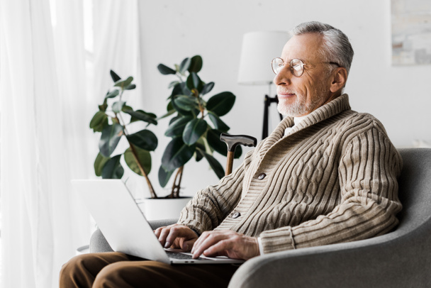 hombre mayor feliz en gafas usando el ordenador portátil en casa
   - Foto, imagen