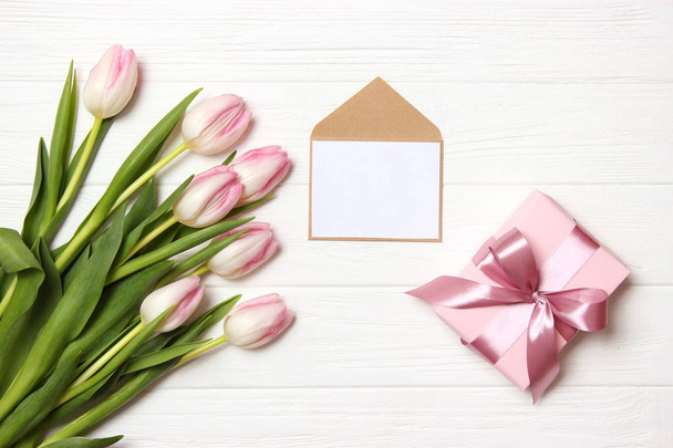 A bouquet of beautiful tulips and a card for text on a wooden background fork on top. Mother's day background, International Women's Day, birthday. Holiday, give. - Foto, immagini