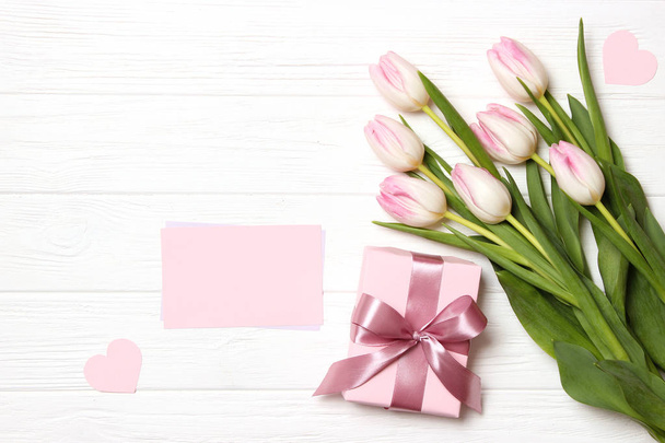 A bouquet of beautiful tulips and a gift on a wooden background top view. Mother's Day Background, International Women's Day. Holiday, give a gift. - Foto, afbeelding