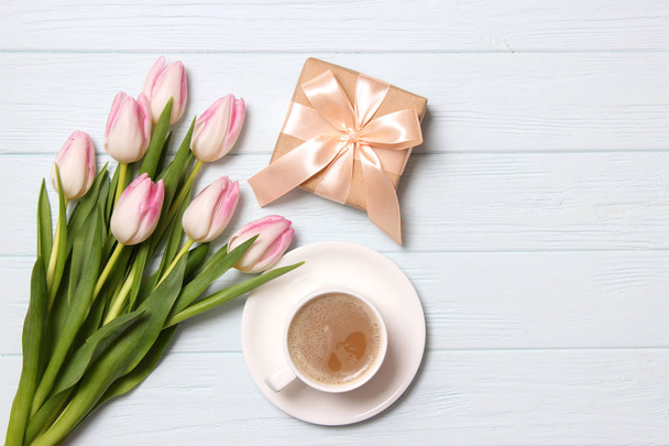 Bouquet von schönen Tulpen, Geschenk und Kaffee auf hölzernem Hintergrund Draufsicht. Muttertag, Weltfrauentag, Geburtstag. Urlaub, beschenke. - Foto, Bild