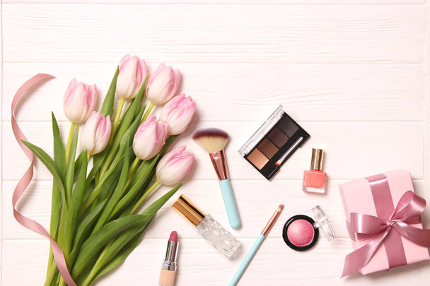 makeup products and beautiful spring flowers on wooden background. Top view. - Valokuva, kuva