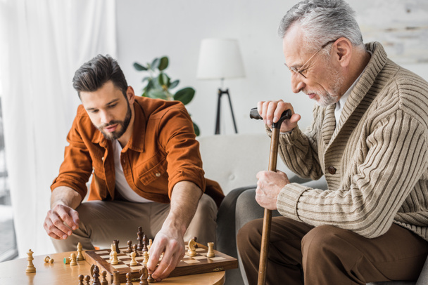 Starszy ojciec w okularach, gra w szachy z synem w domu - Zdjęcie, obraz
