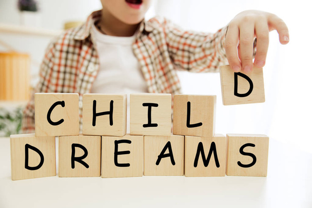 Wooden cubes with words CHILD DREAMS in hands of little boy - Foto, Imagen