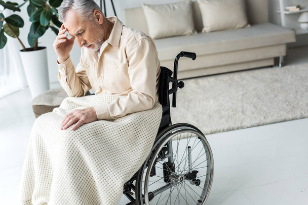 pensive disabled senior man sitting in wheelchair at home  - Valokuva, kuva