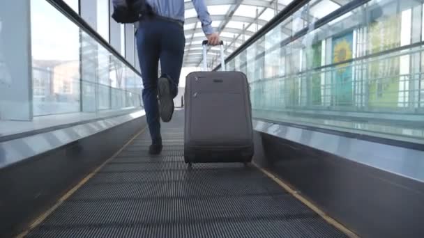 Nohy úspěšný podnikatel běží v hale terminálu a táhne kufr na kolečkách. Kamera sledovat na mladíka s jeho zavazadly je pozdě na letu. Guy rychle na služební cestu. Zpomalený pohyb - Záběry, video