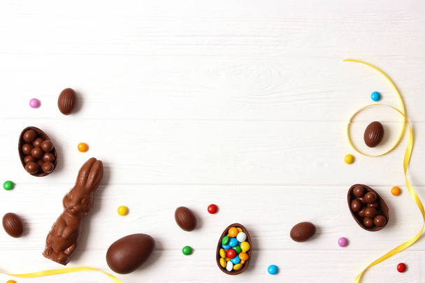 Velikonoční složení s čokoládovými vejci a čokoládovým králíčkem na dřevěném pozadí, místo pro text  - Fotografie, Obrázek