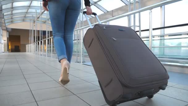 Egy üzletasszony lábai a terminál folyosóján a csomagjaival. Felismerhetetlen lány magassarkúban, aki kerekeken gurul a bőrönddel. A hölgy kirándulni megy. Utazási koncepció. Lassú mozgás Bezárás - Felvétel, videó