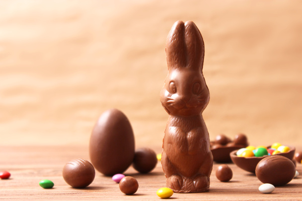 Easter composition with chocolate eggs and chocolate rabbit on wooden background, place for text  - Fotó, kép