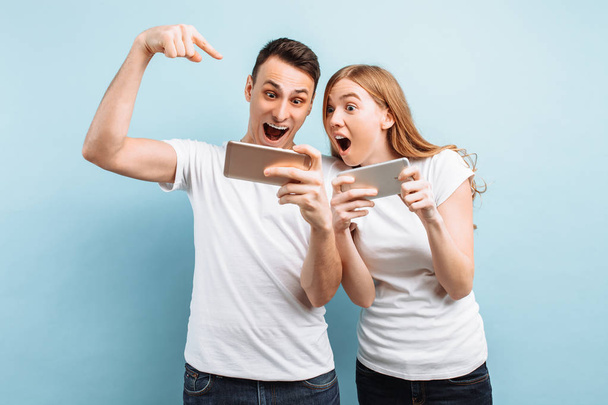 Young excited couple standing , playing games on mobile phones,  - Photo, image