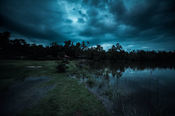 luz de la luna brilla detrás de un nublado en la noche sobre un lago tranquilo
 - Foto, imagen
